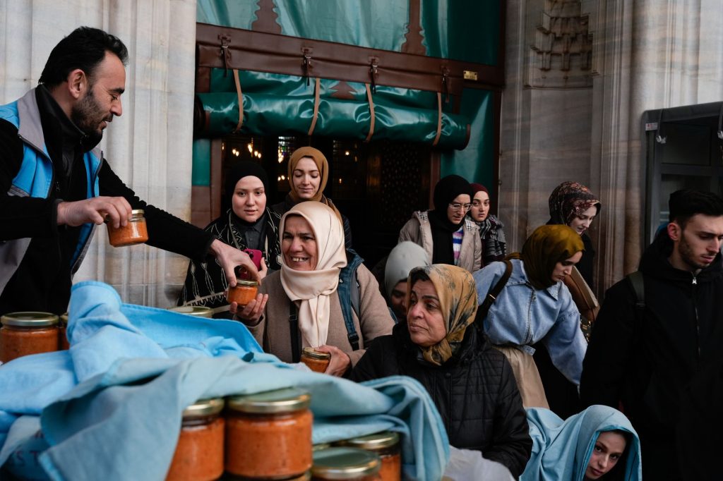 People distributing food jars at a charity event in Istanbul during Ramadan, showcasing community spirit.