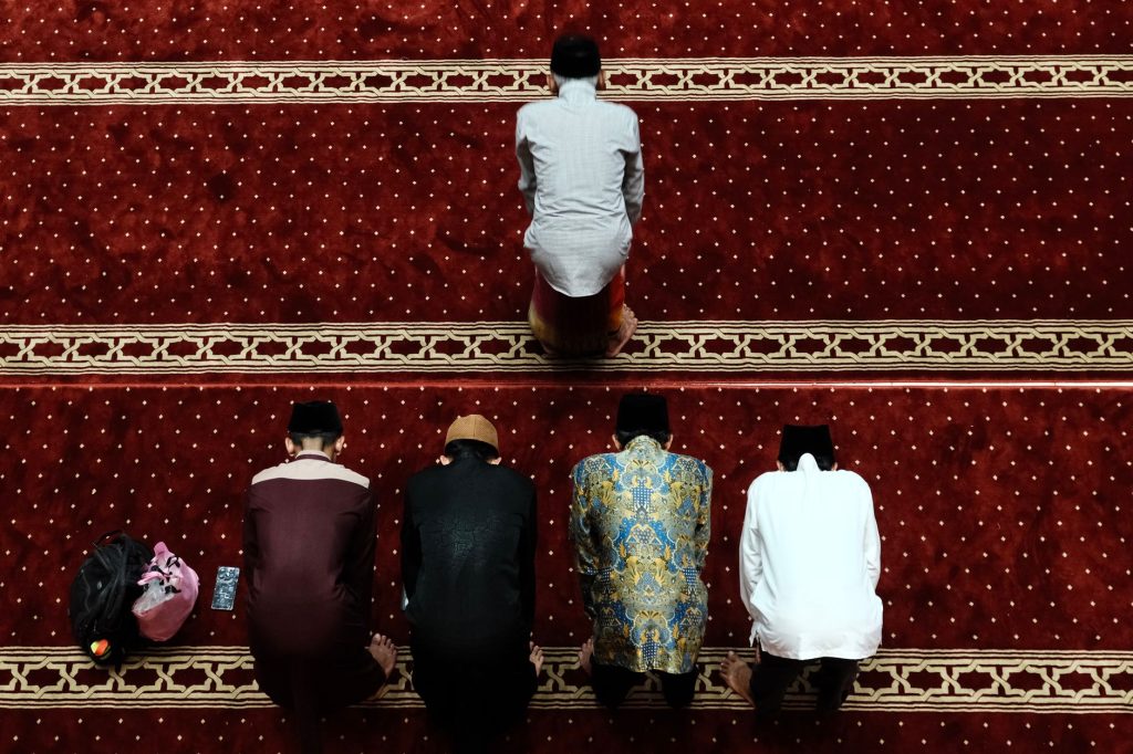 Muslim men performing prayer inside a mosque in Jakarta, Indonesia, captured from above.
